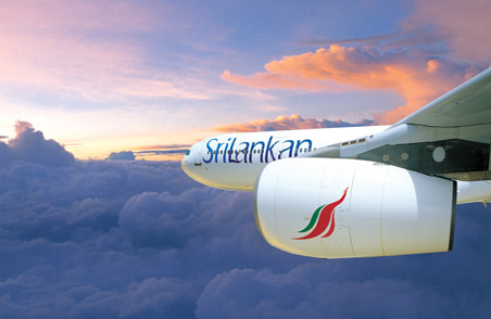 The side view of a SriLankan Airlines plane in flight in the evening sky. The nose of the plane and the engine is visible with SriLankan branding